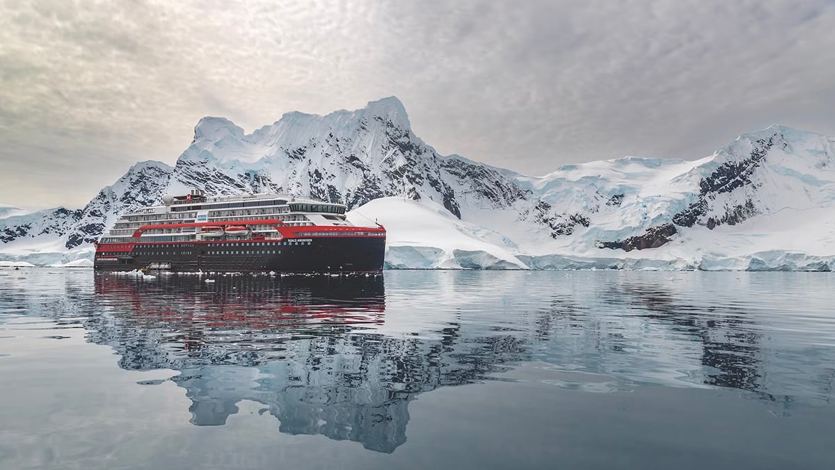 Hurtigruten HX expedition ship with reflection in Antarctic bay